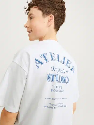 t-shirt blanc oversize ado Description de l'image : "Jeune ado garçon portant le t-shirt blanc oversize ado Jack & Jones , mettant en valeur la coupe volume fit et l'impression au dos. Il est photographié dans un environnement urbain, illustrant le style décontracté et moderne du vêtement, parfait pour les activités quotidiennes et les sorties entre amis en toute saison."